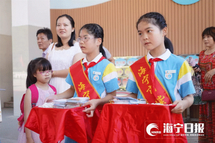 紫微小学校长徐晓良在校门口迎接新生,为他们佩戴校徽,送上成长护照.